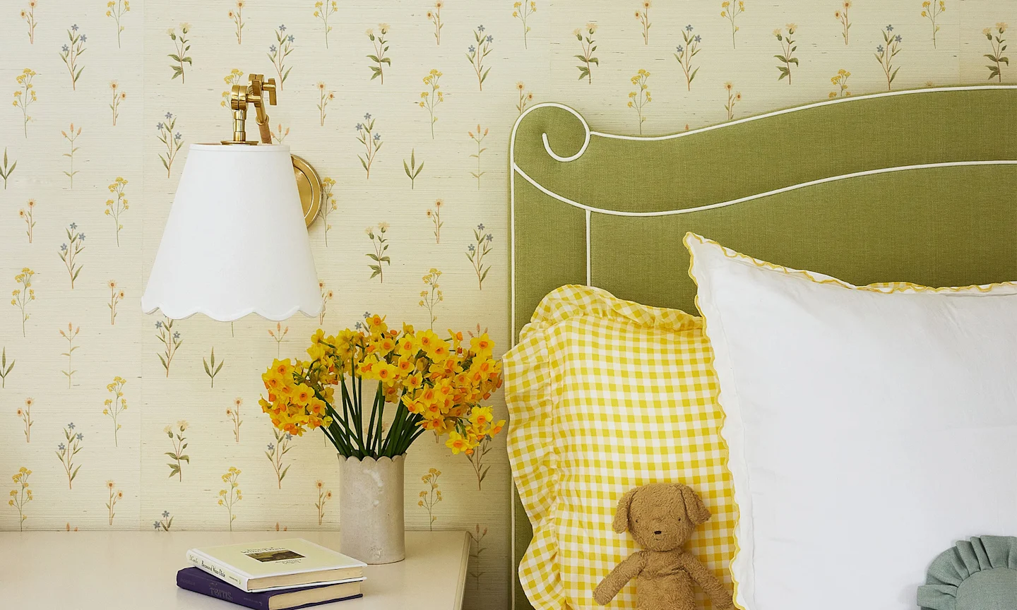 Bedroom with wallpaper a light and airy cottage floral design, a green headboard yellow gingham bedding.