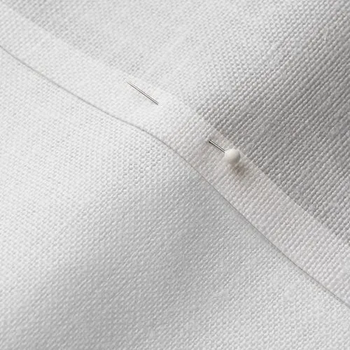 A close-up photo of white fabric with a pin running through it